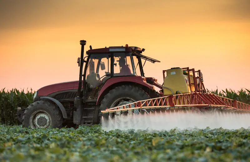 A tractor spraying pesticide on a field