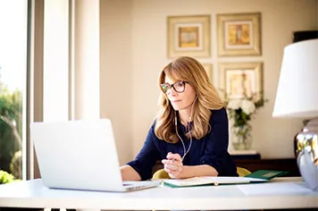 A blond women on her 50's wearing knowledge through content on her computer about agriculture